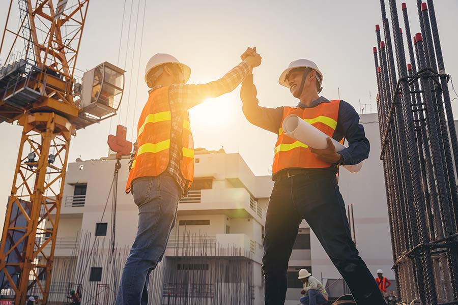 Business Insurance - Two Contractors Standing in a Construction Jobsite Shaking Hands to Celebrate Project Success