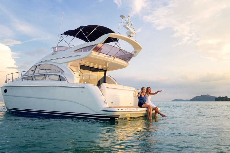 Yacht Insurance - Two Women Sitting on a Luxury Yacht and Pointing Out into the Ocean While on a Summer Vacation